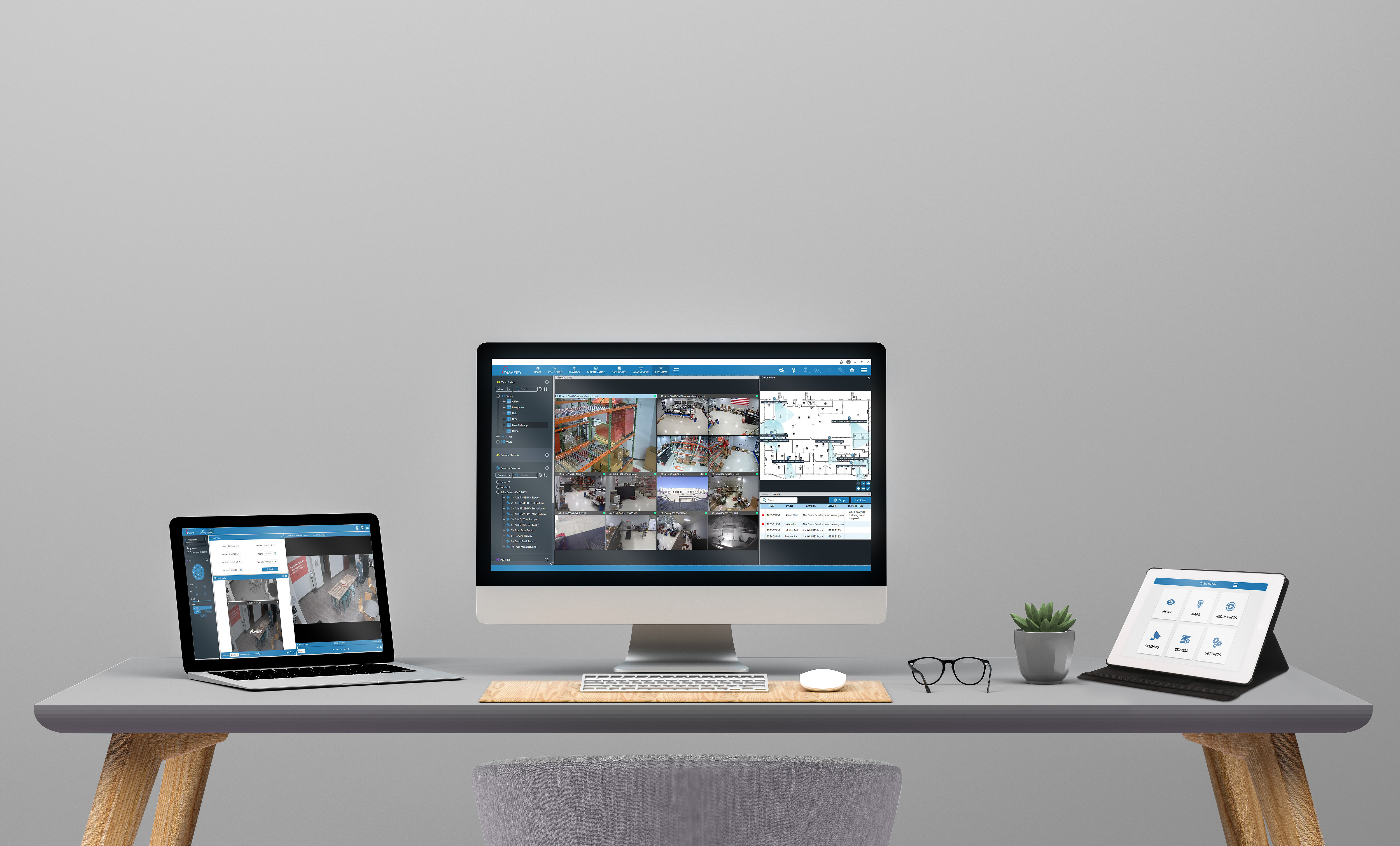 A grey desk with a laptop, desktop computer, and tablet all open for work.