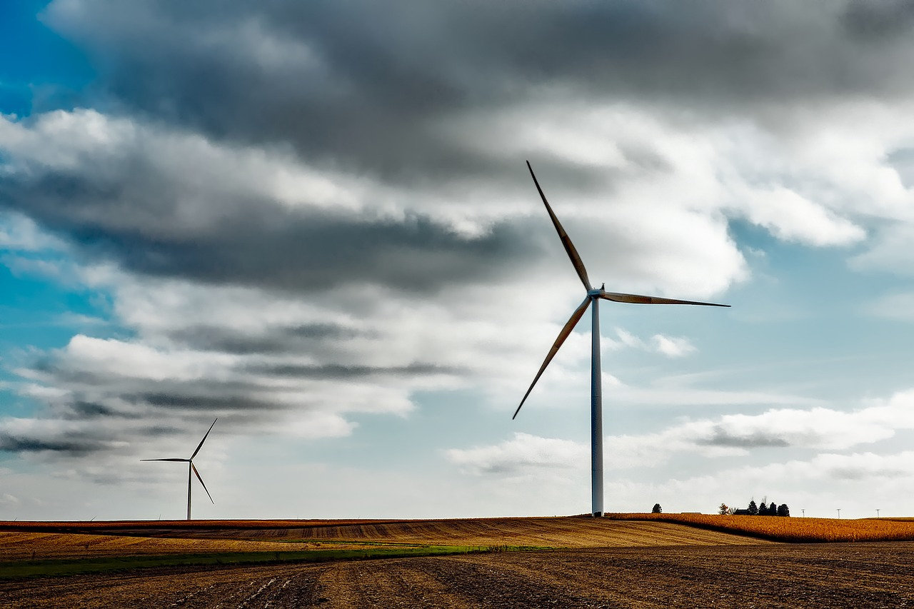 Far off landscape photo of two windmills and a cloudy blue sky