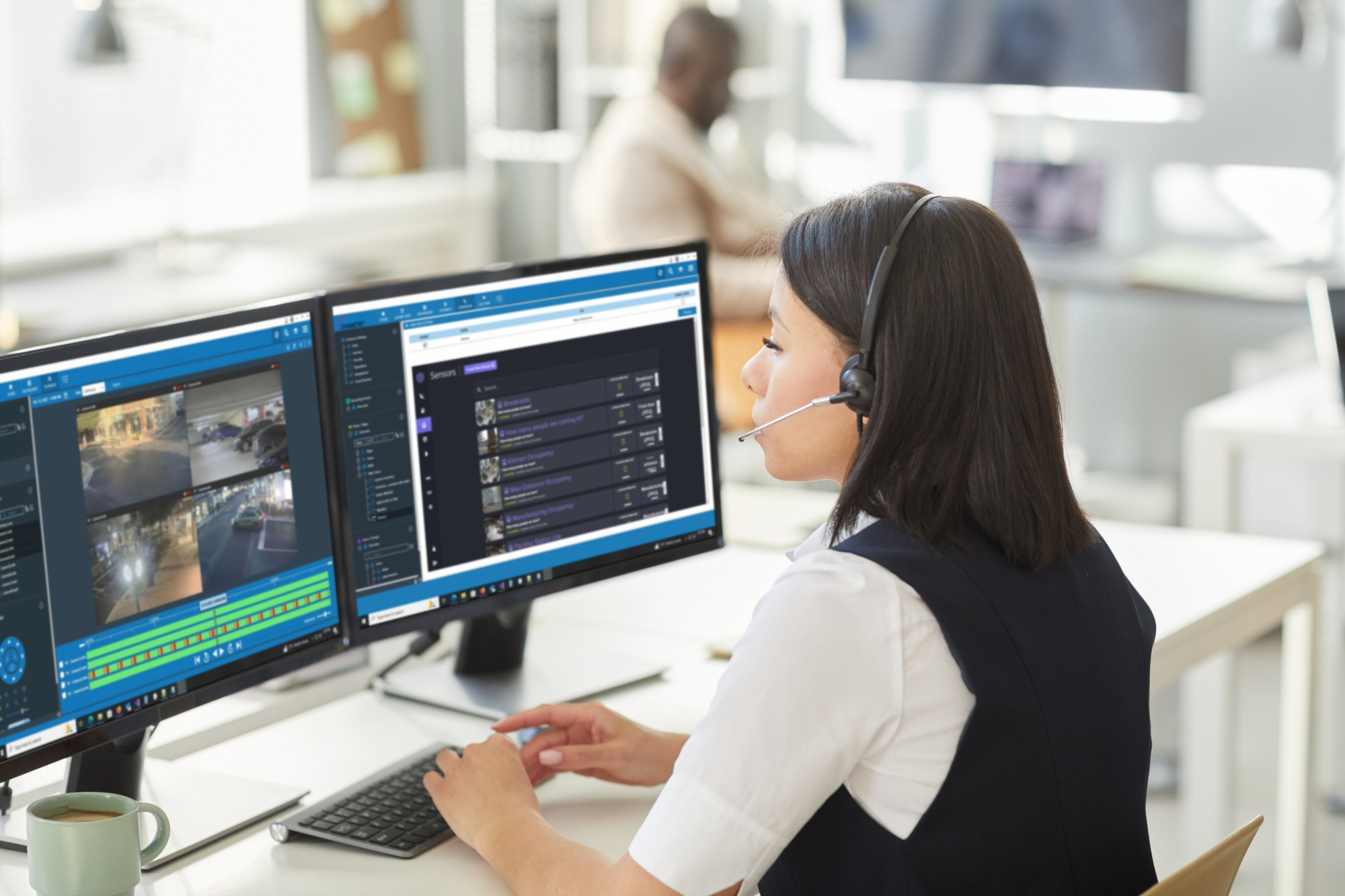 woman working at a desk wearing a headset and multiple computer screens