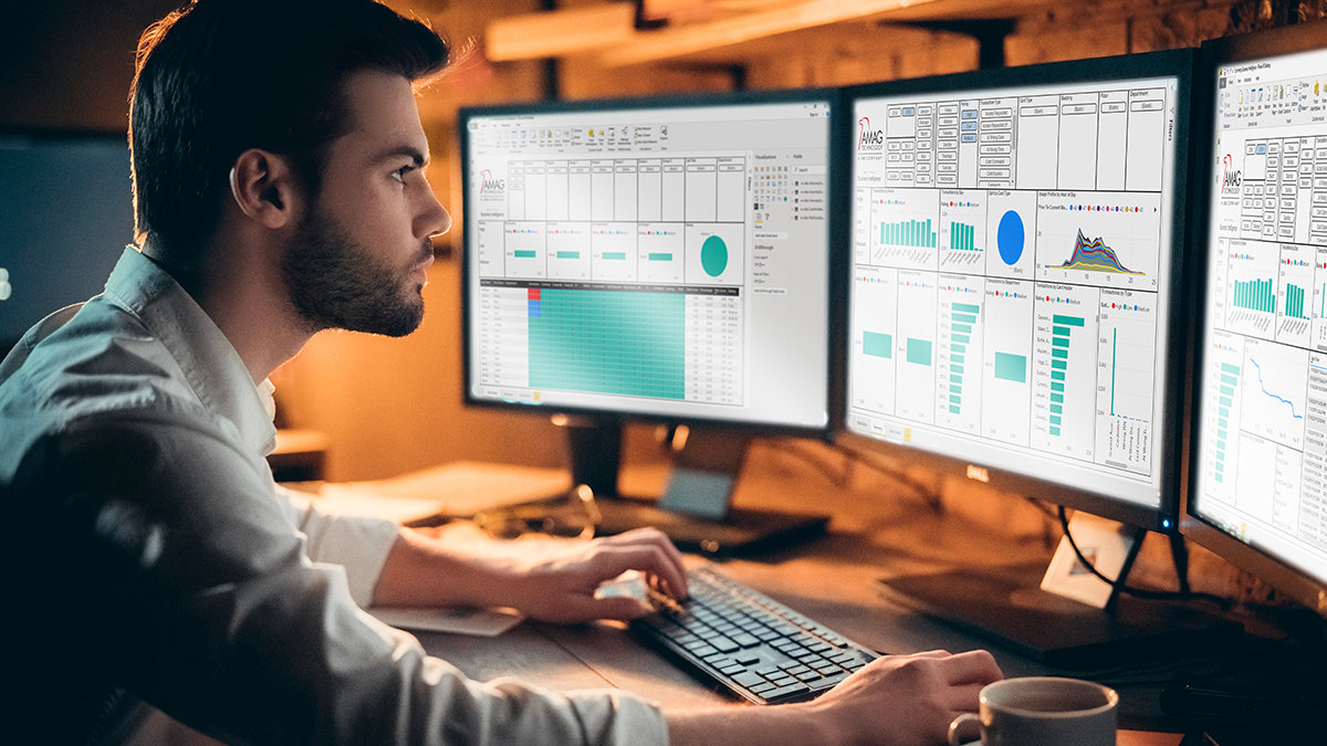 Man working at a desk with three computer monitors