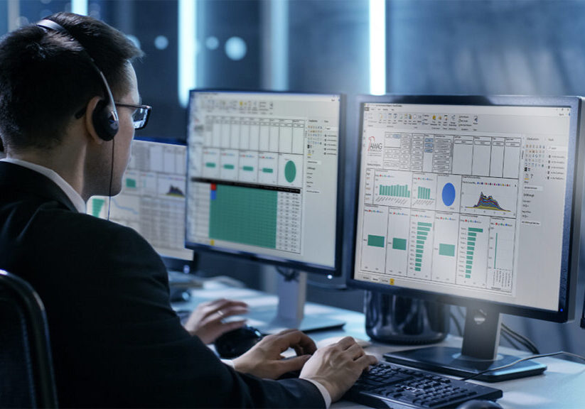 Man working in IT room at computer screen wearing a headset