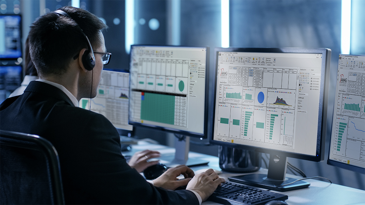 Man working in IT room at computer screen wearing a headset