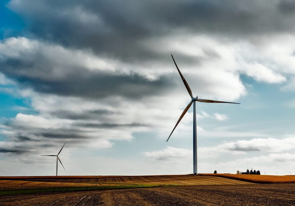 Far off landscape photo of two windmills and a cloudy blue sky