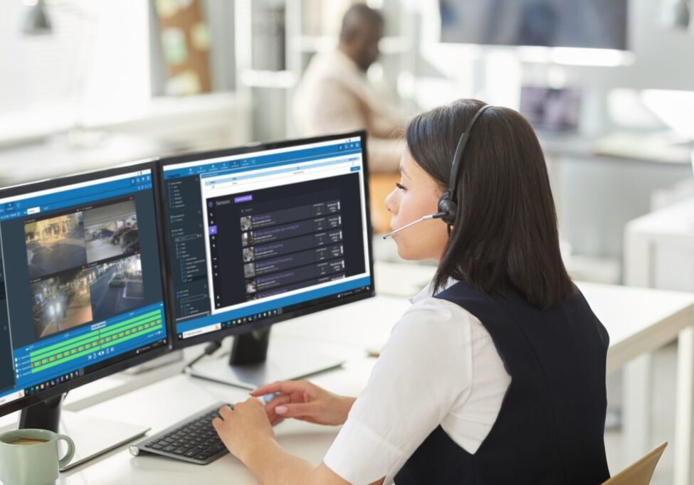 Woman with headset working on computer with dual monitors