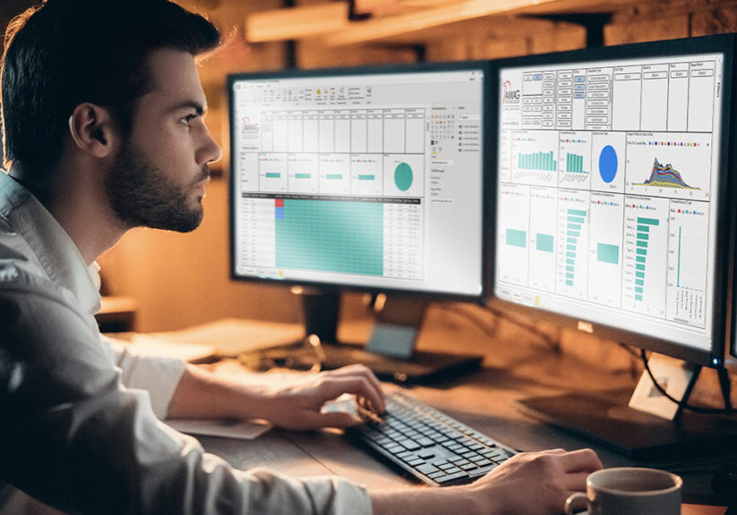 Man working in a dimly lit room. He is working on a computer with three monitors.