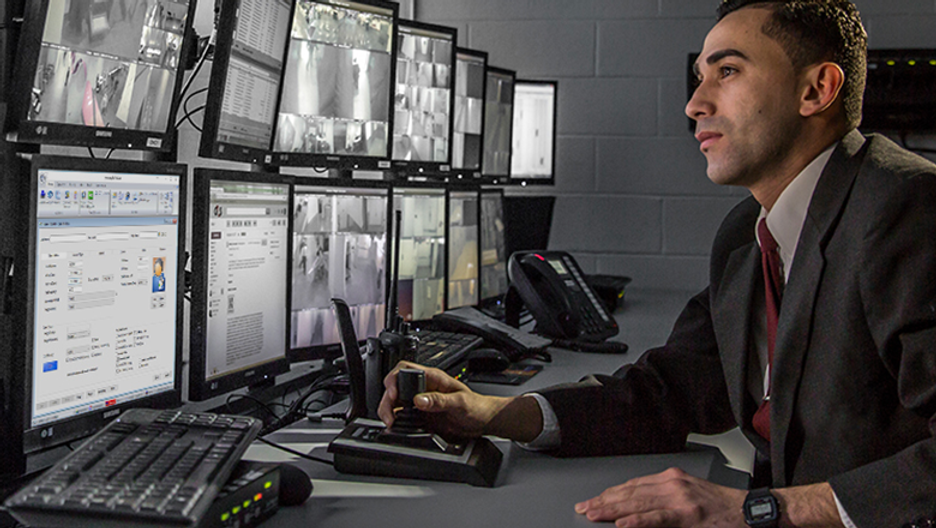 Man working in dimly lit IT room with multiple monitors