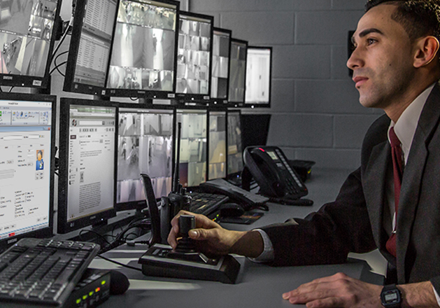 Man working in dimly lit IT room with multiple monitors